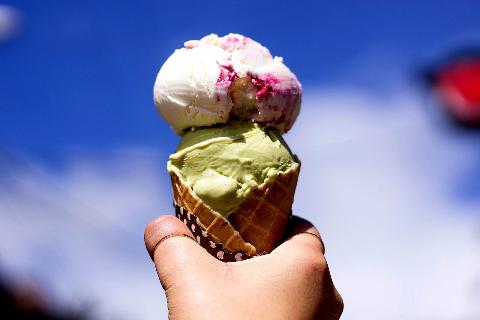 A cone with two scoops of gelato held up against a blue sky